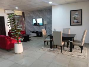 a dining room with a table and chairs and a tv at Derins court in Ibadan