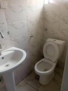 a white bathroom with a toilet and a sink at Derins court in Ibadan
