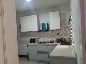 a kitchen with white cabinets and a counter top at Derins court in Ibadan