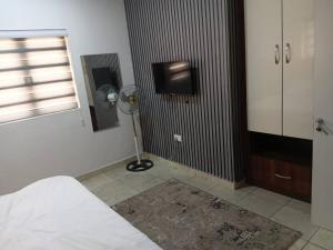 a room with a bed and a fan and a window at Derins court in Ibadan