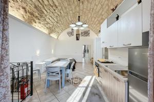 a kitchen with white cabinets and a table with chairs at La Castellana in Monte SantʼAngelo