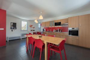 a kitchen with a wooden table and red chairs at Le Chalet des Retrouvailles in Sers