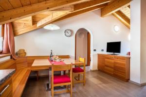 a dining room with a table and a tv at Casa Mirtillo Batistei in Molveno