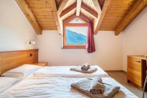a bedroom with a bed with towels and a window at Casa Mirtillo Batistei in Molveno
