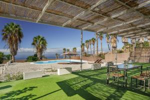 a patio with a table and chairs and a pool at La Casa del Caballo in Adeje