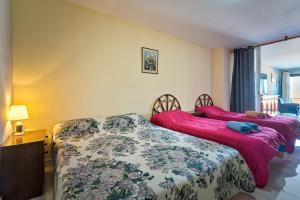 two beds in a hotel room with pink sheets at Casa Meli in Finestrat