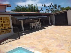 a patio with an umbrella and chairs and a pool at Cachoeira Paulista Espaço Cassicay in Cachoeira Paulista