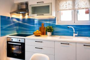 a kitchen with blue walls and white cabinets and a sink at Jenny Apartment in Gaios