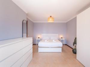 a white bedroom with a bed and two tables at Costa Fortuna in Poris de Abona