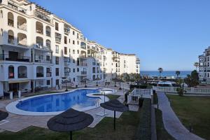 a hotel with a swimming pool in front of a building at Marina de la Duquesa 805 in Manilva