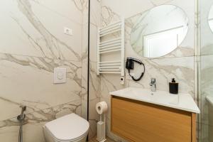 a bathroom with a sink and a toilet and a mirror at Fluctus Apartments in Durrës +186 photos