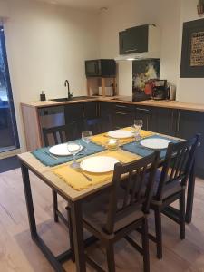 a wooden table with chairs and glasses on it in a kitchen at Le Ty Gîte - Sud Morbihan in Théhillac
