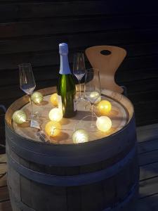 a wine bottle and glasses on a barrel with lights at Le Ty Gîte - Sud Morbihan in Théhillac