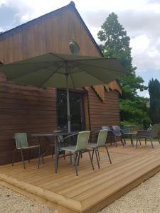 a table and chairs with an umbrella on a deck at Le Ty Gîte - Sud Morbihan in Théhillac +6 photos