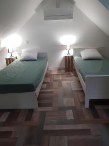 two beds in a room with wooden floors at Le Ty Gîte - Sud Morbihan in Théhillac