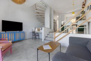 a living room with a couch and a tv and stairs at La Casa de las Hesperides in Morro del Jable