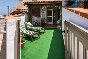 a balcony with a green floor and two chairs at Apartamento el Carmen in El Cotillo