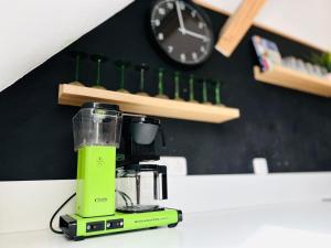 a green blender sitting on a counter with a clock at Traum-ferienwohnung in Siegsdorf