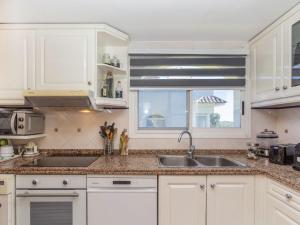 a kitchen with white cabinets and a sink and a window at Apartment Coco Golf by Interhome in Sant Jordi +18 photos