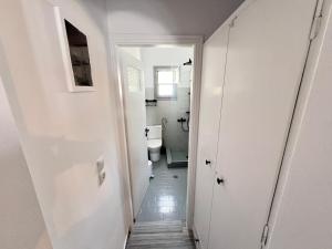 a white bathroom with a toilet and a hallway at aeolian blu 3 in Parikia +33 photos