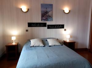 a bedroom with a blue bed with two lamps at Les Chambres Des Chtis in Abbeville