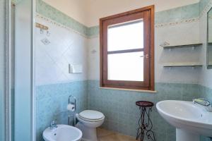 a bathroom with a toilet and a sink and a window at Villamara in Olìa Speciosa