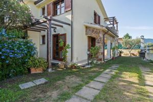 a white house with a yard with blue flowers at Villamara in Olìa Speciosa