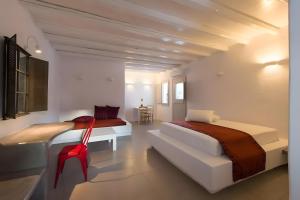 a white bedroom with two beds and a red chair at Echinousa Kimolos katoikia no5 in Kimolos