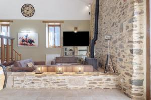 a living room with couches and a stone wall at Le Ranch Des Ours in Champsac