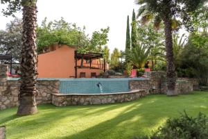 a swimming pool in a yard with palm trees at La Jacaranda in Hornachuelos