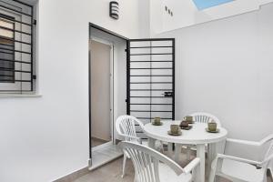 a white dining room with a white table and chairs at Apartamento Guzmán A in Barbate