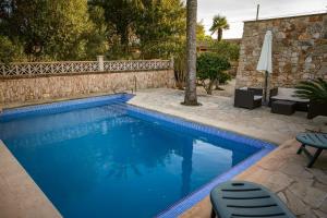a swimming pool with two chairs and a table at Villa moli de ca n'orell in Santanyi