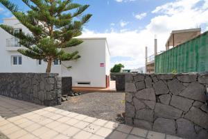 a retaining wall next to a house with a tree at Casa Rosi in Tinajo