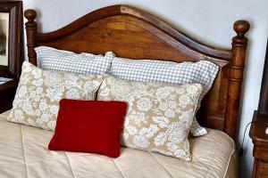 a bed with a wooden head board with pillows and a red pillow at A Casa dos Raminhos in Vila de Frades