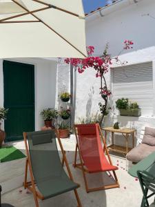 a patio with chairs and an umbrella at A Casa dos Raminhos in Vila de Frades