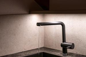 a sink with a faucet with water coming out of it at Apartments Perfila Morgenrot in Valdaora