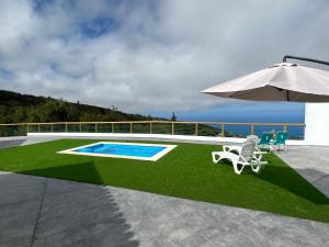 eine Terrasse mit Sonnenschirm und Stühlen sowie ein Pool in der Unterkunft Stevier in Icod de los Vinos