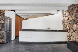 a kitchen with white cabinets and a stone wall at La Bodeguita House in Haría