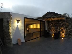 a building with a stone wall and a patio with a table at La Bodeguita House in Haría