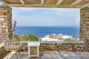 a stone patio with a table and a view of the ocean at Casa Xyla-sunset view villa in Melissaki