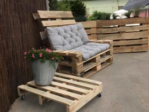 a wooden bench with a chair and a potted plant at Gut Bennewohld in Heide
