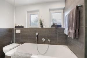 a bathroom with a bath tub and a toilet at Ferienwohnung Schneider in Blaubeuren +31 photos