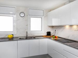 a kitchen with white cabinets and a clock on the wall at Villa Mi Capricho by Interhome in Calafell