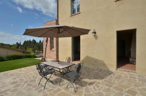 a table and chairs with an umbrella on a patio at Appartamento Pino in Trequanda