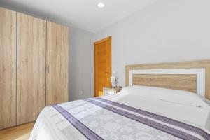 a bedroom with a white bed and wooden cabinets at 4 Jardin- Puerto Chico in Llanes
