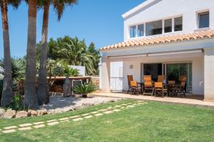 a white house with palm trees and a patio at Abatzer in Ciutadella