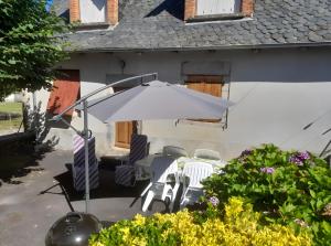 a table and chairs and an umbrella in front of a house at La Maisonnette in Goulles