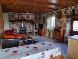 a living room with a table and a stone fireplace at La Maisonnette in Goulles