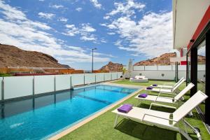 a pool on the roof of a house with lounge chairs at Villa Tauro 31 in Mogán