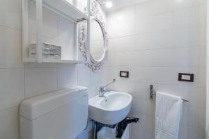 a white bathroom with a sink and a mirror at Casamari nel centro di Marzamemi in Marzamemi